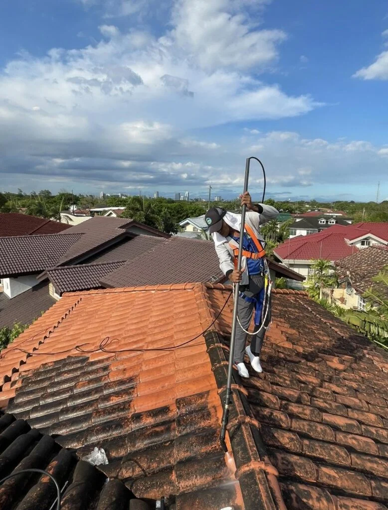 TopMop crew rinsing clay roof tiles with cleaning equipment during the Quezon City project
