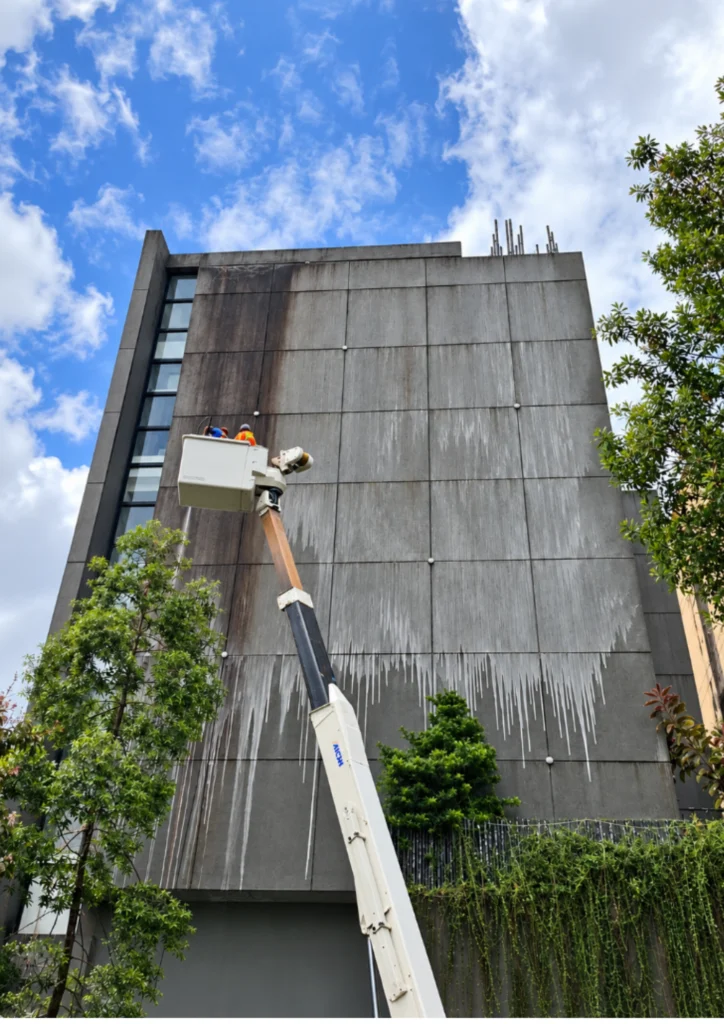 Wide view of manlift-assisted facade cleaning in progress in Valenzuela